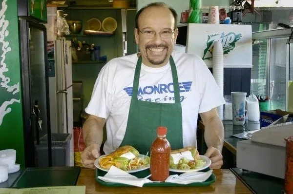 Smiling man serving food at counter.