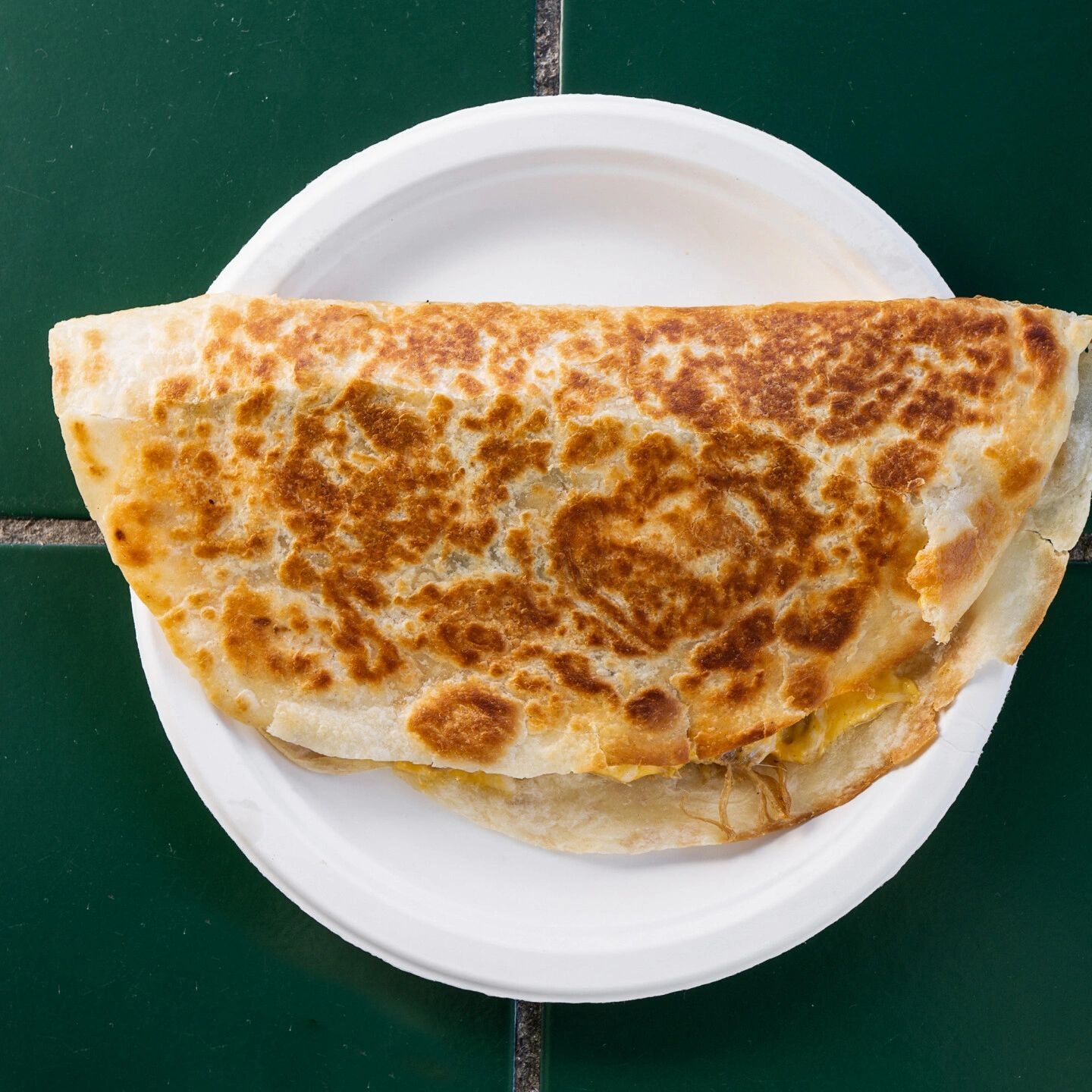 Folded cheese quesadilla on paper plate